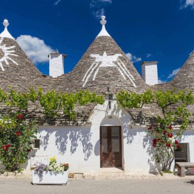 Beautiful town of Alberobello with trulli houses among green plants and flowers, main touristic district, Apulia region, Southern Italy